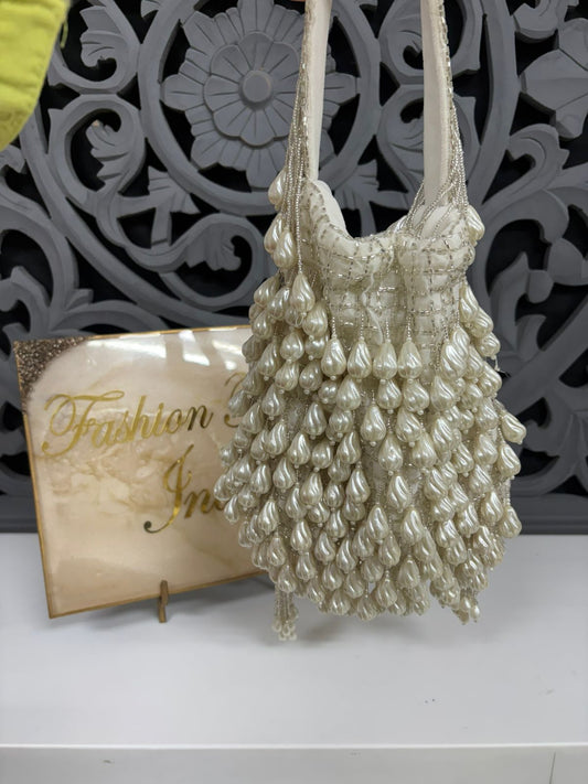 Pearl-handled handbag on a white surface with decorative background