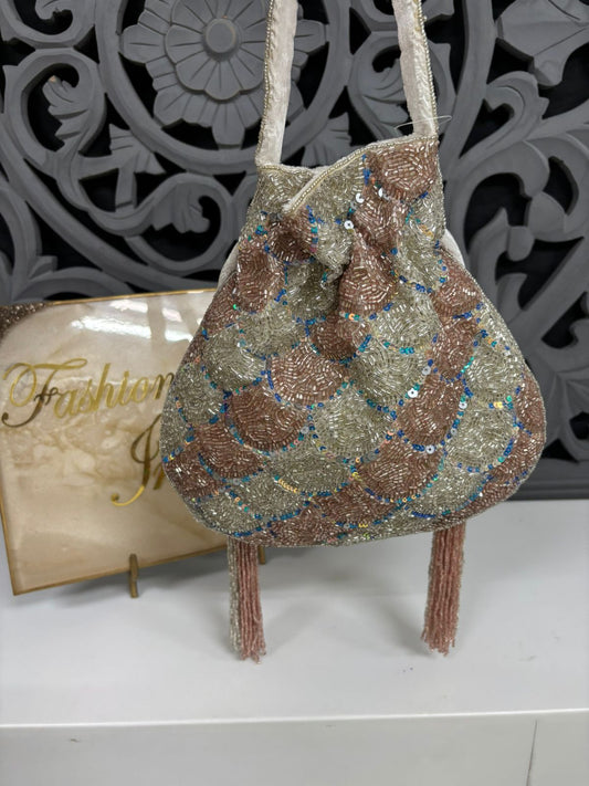 Decorative handbag with sequins and beads on a white surface with a decorative gray background.