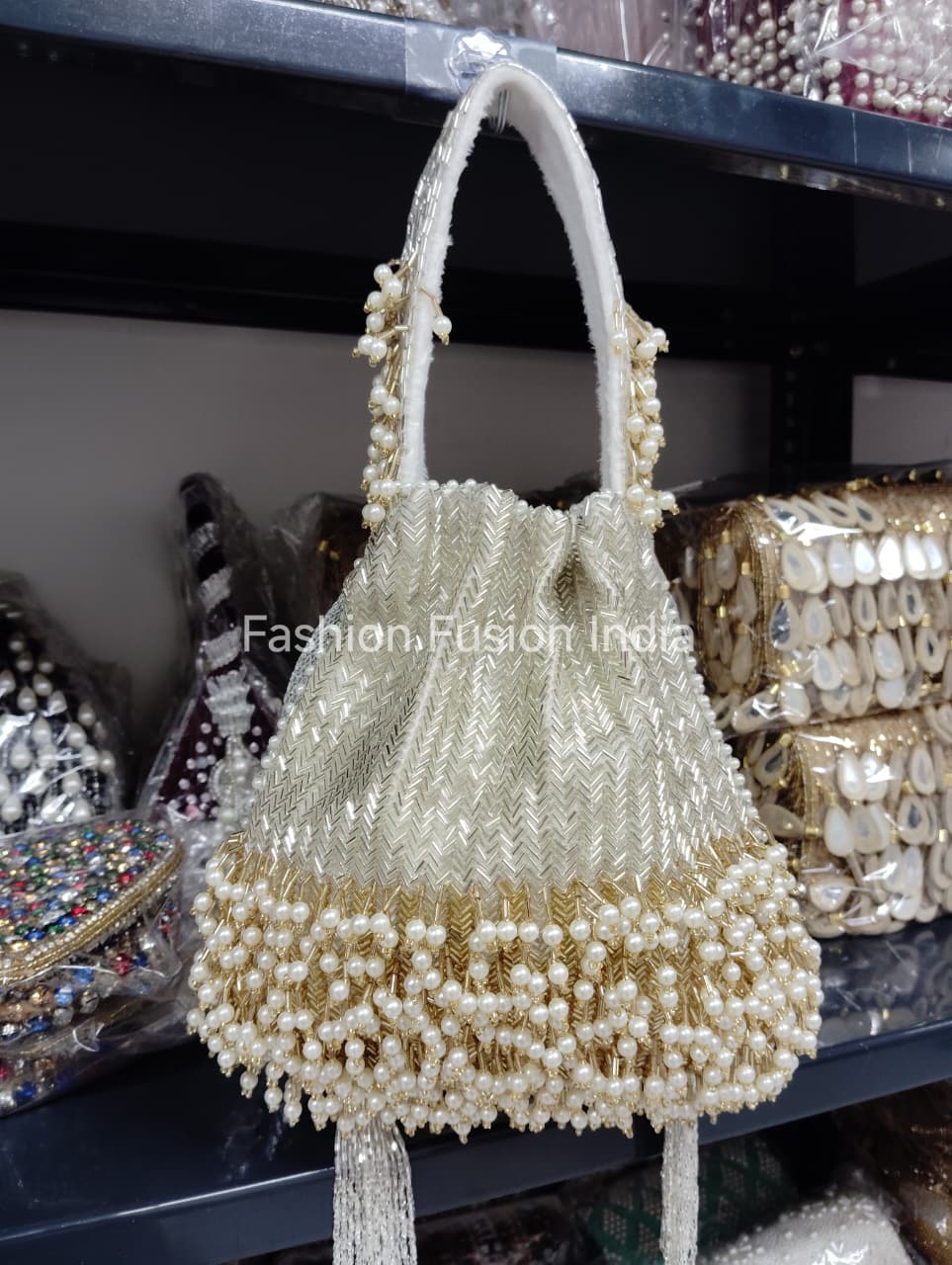 Beaded handbag with pearl details on a stand, with 'Fashion Fusion India' branding.