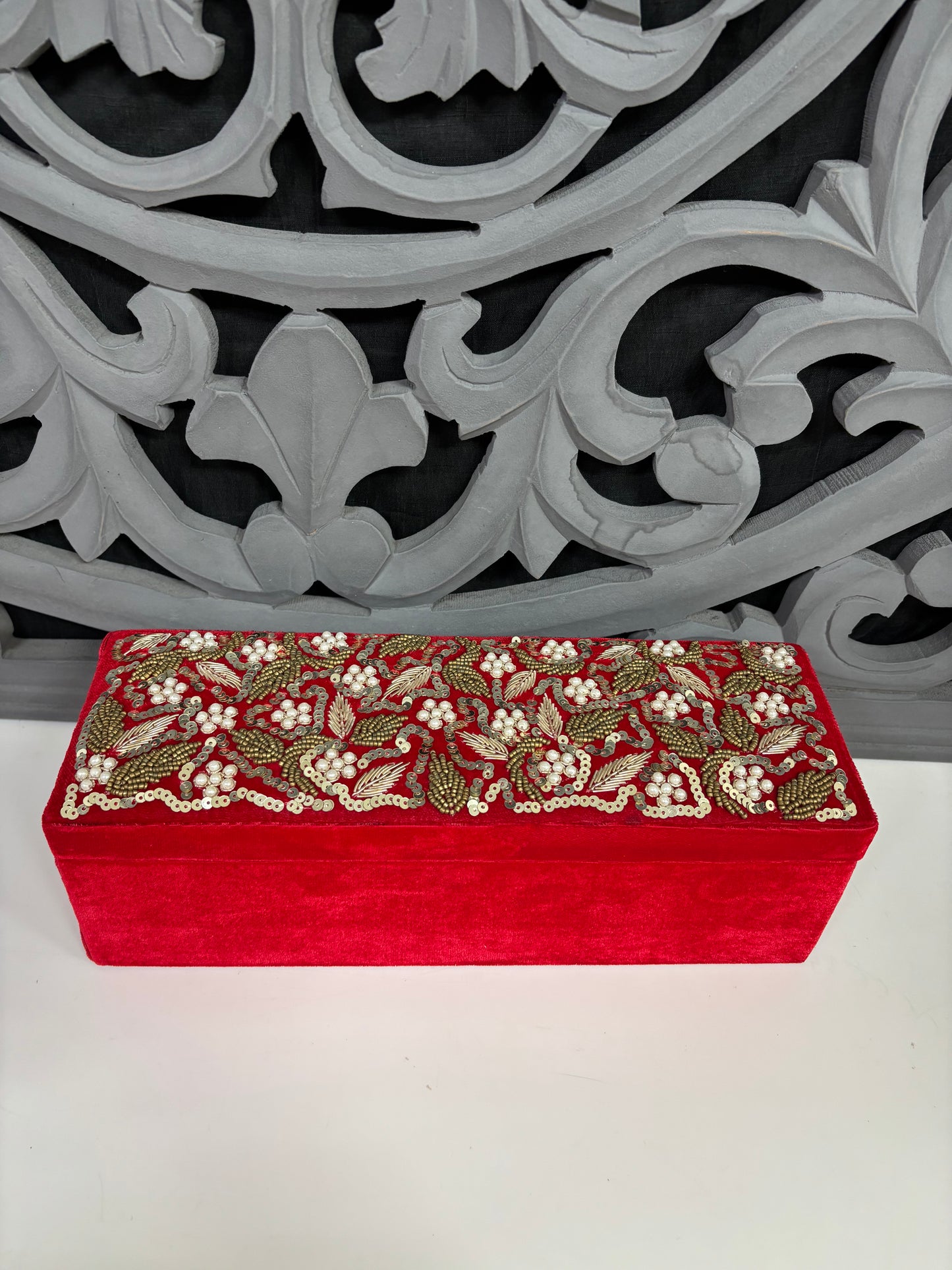 Red decorative box with floral patterns on a white surface with a gray decorative background