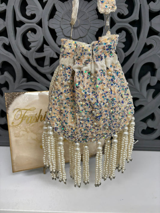 Decorative handbag with pearl fringes and intricate design in the background